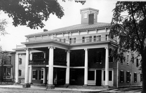 Large three story hotel with a deck and pillars.