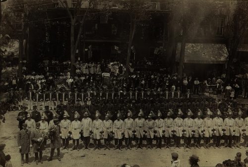 A Parade of Fire Fighters in front of a hotel.