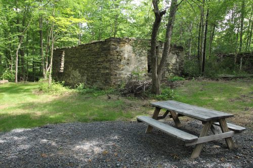 Picnic table next to remains of stone building without roof.