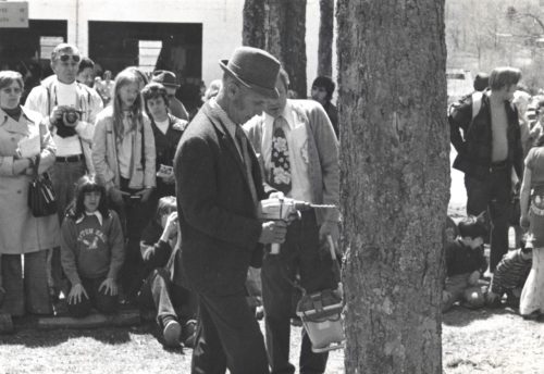 Man tapping Maple Tree in front of crowd.