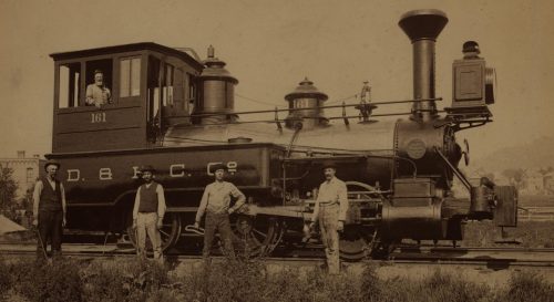 Train engine with four people outside and one person inside.