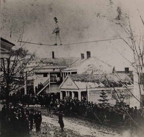 Man walking on a tight rope with a crowd watching.