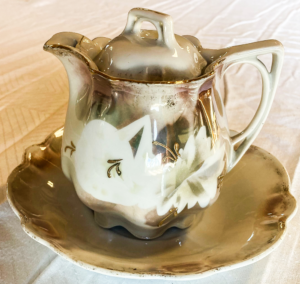 Green and White Tea pot on a small green and white plate.