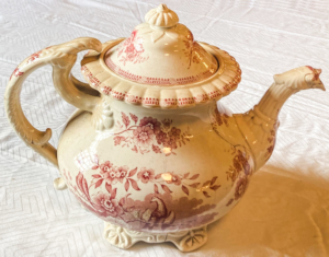 Cream colored tea pot with pink flower pattern.