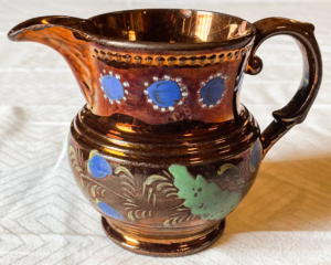 Brown pitcher with blue circles and green leaves.