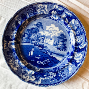 Blue plate with flowers and illustration of mother and child with a dog.