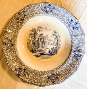 White and blue plate with flowers and trees.