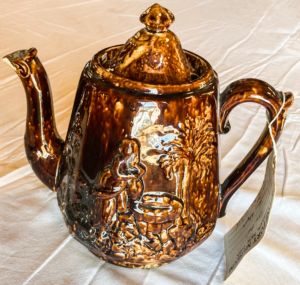 Brown teapot with woman by the well engraving.