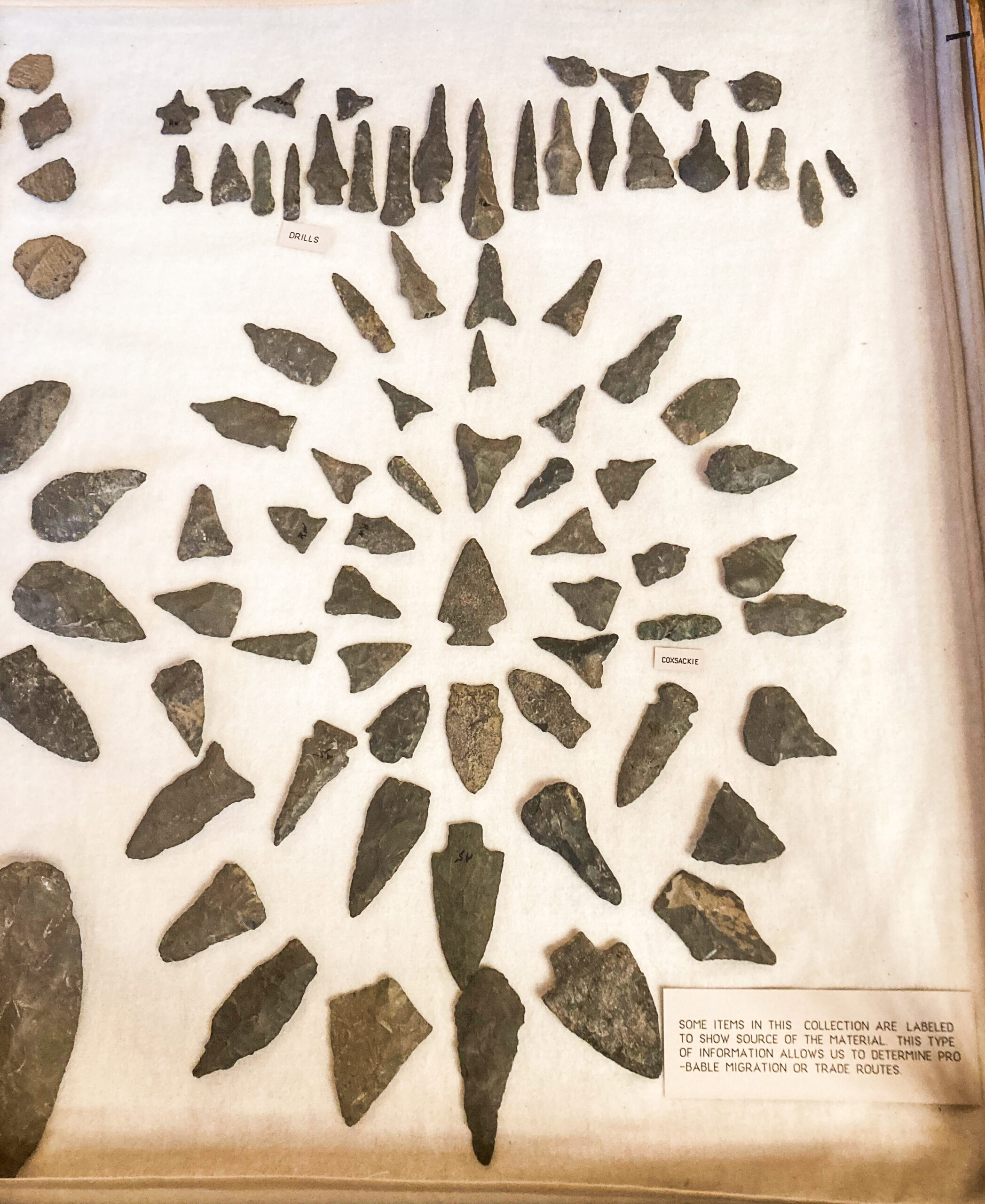 Sign in the case that reads "Some items in this collection are labeled to show source of the material. This type of information allows us to determine probable migragration or trade routes."