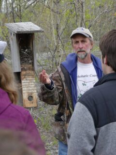 Kevin Berner in front of a bluebird enclosure presenting in front of a group of people