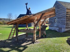 Two men building roof for bee hive oven.