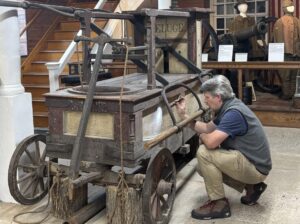 Josiah Wagener Performing a Conservation Assessment on the Deluge Fire Engine.