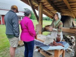 Woman in colonial attire giving demonstrations of the beehive oven.