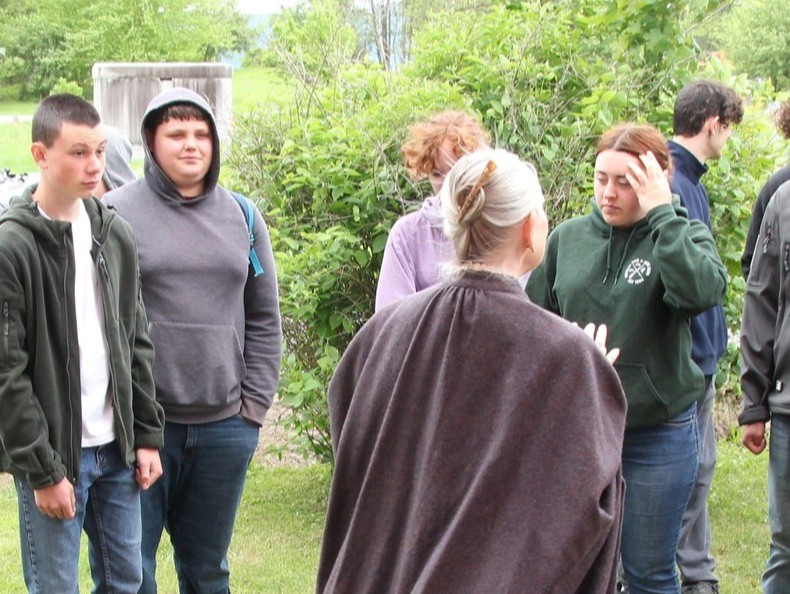 School marm inviting a school group into the schoolhouse.