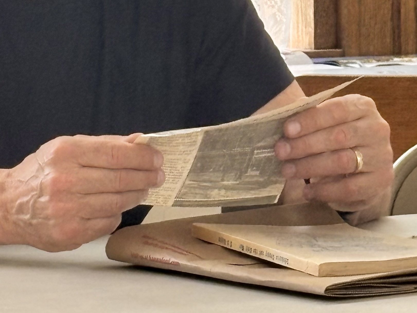 Close up of a man's hands holding a newspaper clipping.