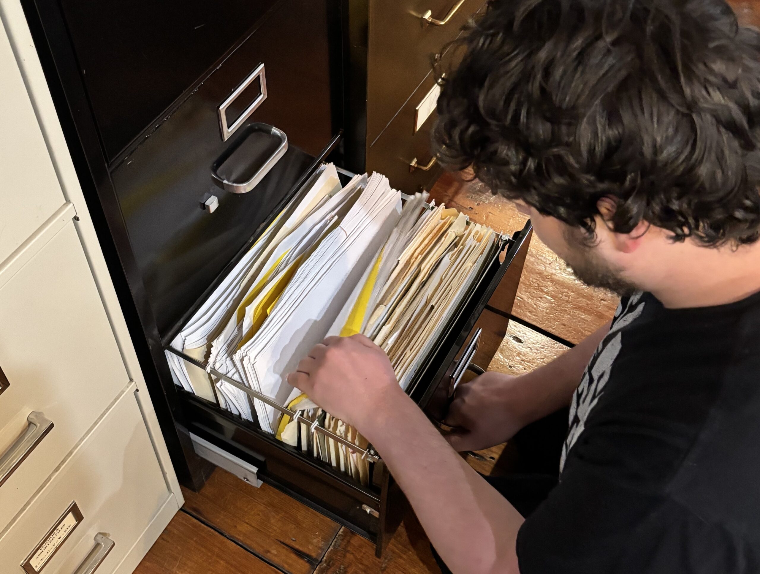 Man looking through a filing cabinet.