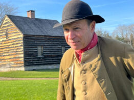 Man dressed in colonial attire outside of the Hartmann's Dorf House.